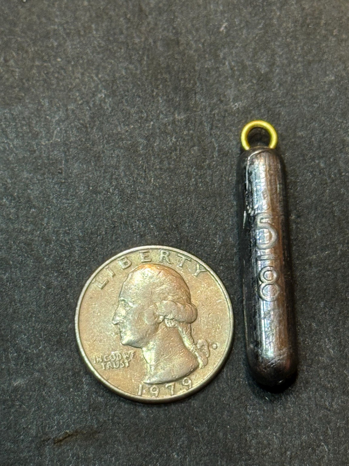 ForgeCast 5/8 oz pencil weight beside a U.S. quarter for size reference